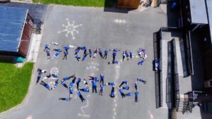 Drone image of Abermule School showing children positioned in the playground spelling "Growing Together"